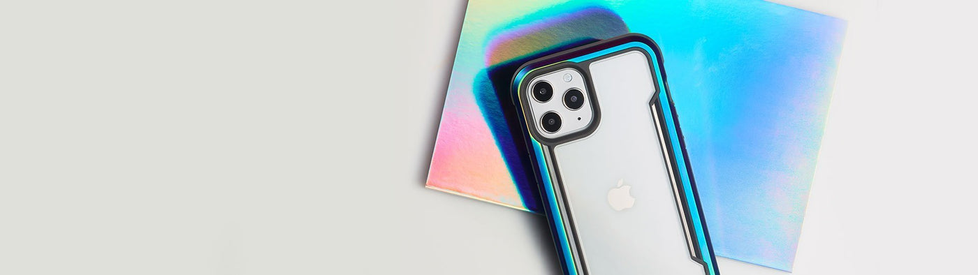 iPhone 12 Pro with Raptic Shield in Iridescent case, laying down on iridescent paper with camera facing up