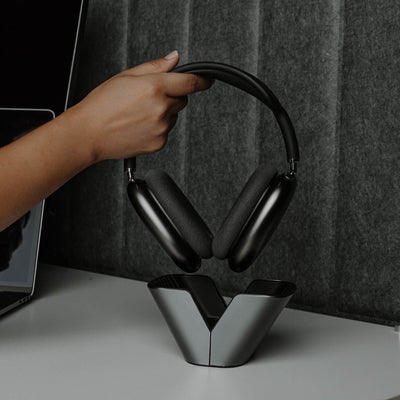hand holding AirPods Max Heaphones lowering into Raptic Base Stand on a desk