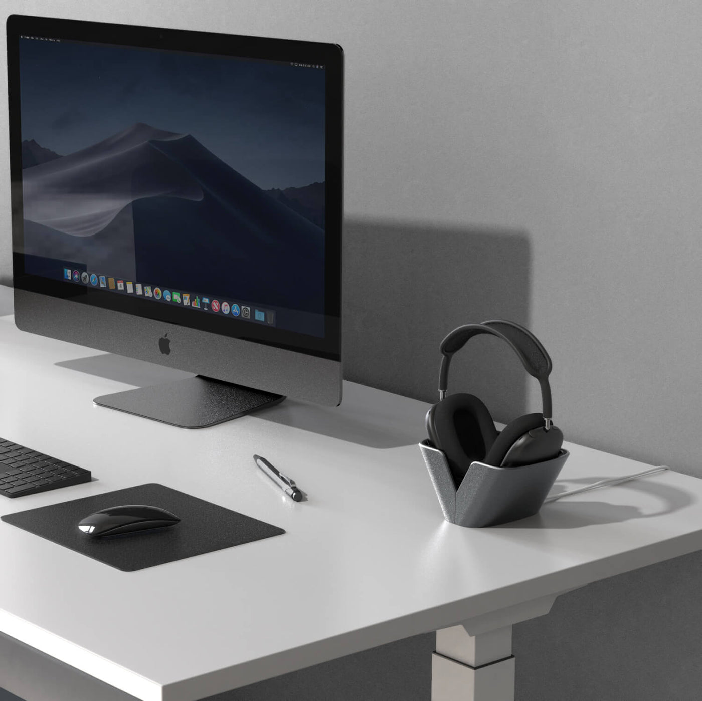 Office desk with computer, mouse, keyboard, and AirPods Max headphones inside Raptic Basestand